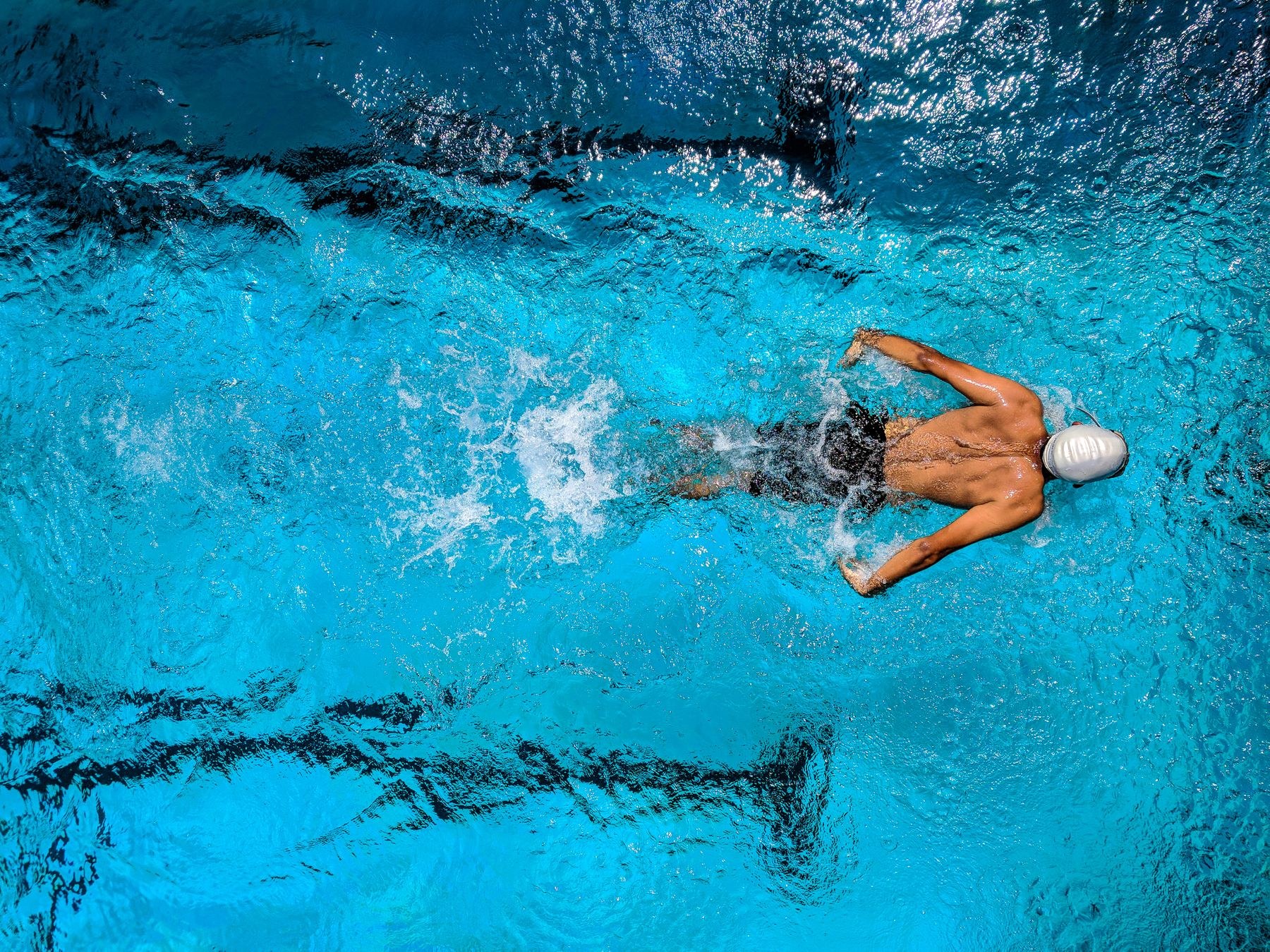 A swimmer moving through clear blue water in an outdoor pool